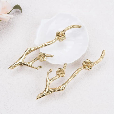 Slick Twig Drawer Pulls In Polished Brass Plum Blossom Branch Handle For Cabinets And Dressers resting on white surface