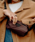 Person holding Ultralight Terra Shell Packing Cube Weatherproof Luggage Organizer, size S, in brown, attached to coat