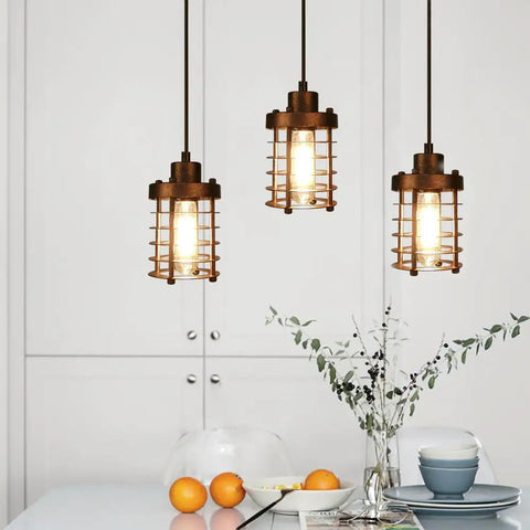 Three Pack Rustic Pendant Lights With Mini Metal Cage Shades In Bronze Finish Industrial Vibe Edison Style Hanging Fixtures For Kitchen Island Bar Foyer With Easy Hardwire Install hanging in a kitchen setting.