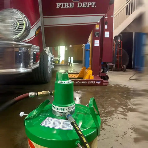 Beefed Up Air Powered Grease Pump Kit with Booster Gun in use near fire truck lift, 5 gal pail, 10000 PSI, 16 oz/min flow.