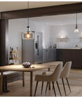 Latrobe Collection 1 Light Clear Glass Coastal Pendant Light In Matte Black illuminating modern dining area