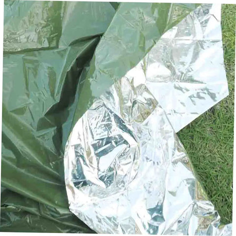 Reflective thermal emergency blanket from Three Piece Camping Survival Kit With Reflective Thermal Emergency Blanket And First Aid Gear For Beach Hiking Camping Outdoor Adventure In All Weather on grass.