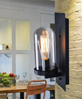 Upgrade Your Home Decor Game With This Killer Vintage Loft Wall Sconce Featuring Rust Resistant Iron Shade And Rock Solid Wood Base Designed For Effortless Bedroom Or Hallway Glow. Vintage black wall sconce with clear glass shade and Edison bulb in a dining area.