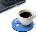 White coffee cup on round blue coaster near laptop