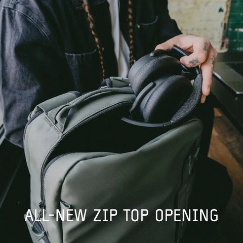 Person placing headphones in Prvke Zip 21L V4 Photography Bundle Weatherproof Travel Camera Backpack with open zip top.