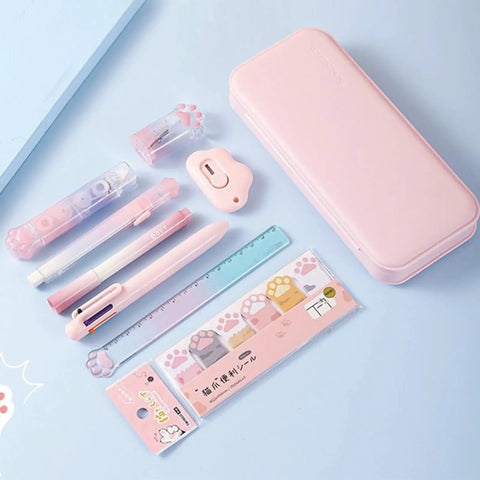 Pink Cat Paw Stationery Set Must Have For School And Office Cute Kawaii Desk Supplies With 9 Pieces Including 6 In 1 Ballpoint Pen Highlighter Eraser 2 In 1 Correction Tape And Glue Utility Knife Ruler Pencil Sharpener Memo Pads And Plastic Case displayed on blue surface.