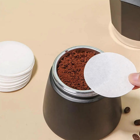 Hand placing 500 Count Round Disposable Coffee Filters Paper Micro Filters For Aeropress Brew Replacement over coffee grounds in brewer.
