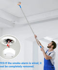 Say No To Wobbly Ladders With This Smart Smoke Detector Removal Tool Featuring An Adjustable Reach Pole Stretching Up To 10 Feet For Easy Ceiling Disassembly And Hassle Free Maintenance. A user extends the pole to remove a smoke alarm.