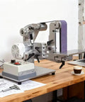 Powerhouse 750W Belt Sander With 915X50mm Sanding Belt For Metal And Wood Projects on a wooden table with blueprints.