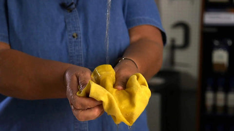 Game Changer Pre Treated Wood Furniture Dusting Cloths Pack Of Five Lint Free Wipes being wrung out for cleaning.
