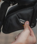 Close-up of hands interacting with the Aero Wedge Pack DX Medium Under Saddle Bag 0.9 L Expanding Capacity With QuickClick F25 Mount.