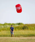Person flying Fluxx 1.3 R2F Trainer Kite For Beginners in a grassy field, showing easy launch and stable flight.