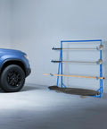 Legit Heavy Duty Steel Cantilever Storage Rack With 440 Lb Capacity Adjustable Arms for PVC pipes, featuring metal shelves beside a vehicle.