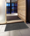 Grippy Non Slip Rubber Drainage Floor Mat With Holes 24x36 Anti Fatigue Cushion placed in a modern entryway over tile flooring.
