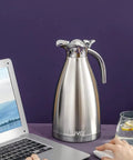68oz Double Wall Stainless Steel Thermal Carafe With Vacuum Insulation Press Button Top Coffee Pot next to a laptop and glass.