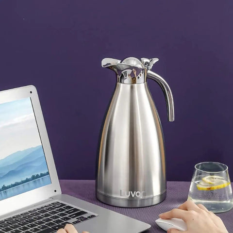 68oz Double Wall Stainless Steel Thermal Carafe With Vacuum Insulation Press Button Top Coffee Pot next to a laptop and glass.