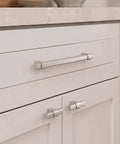 Close-up view of 10 Pack Brushed Nickel Single Hole Kitchen Cabinet Knobs on white cabinets, showcasing sleek anodized aluminum finish.