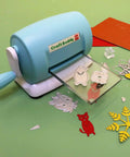DIY Die Cutting And Embossing Machine For Crafting Scrapbooking Card Making And Papercrafts on a table with cut shapes