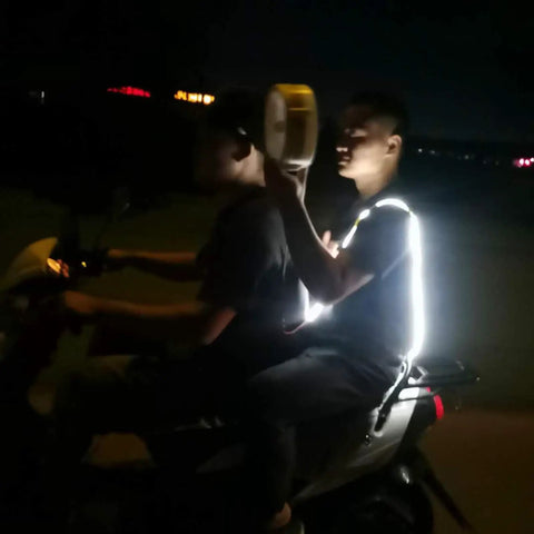 Two people on a scooter at night, one holding a Dual-Mode Portable Wind And Water Turbine Generator For Outdoor Power Small Hydroelectric Micro Turbine.