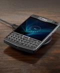Tough As Nails Rugged QWERTY Smartphone Powered By Rock Solid Android 10 Platform resting on a wireless charger on a wooden surface.