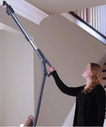 Woman using Heavy Duty Bagged Canister Vacuum on ceiling corner; swivel head for easy navigation and cleaning.