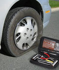 Knuckle Tough Roadside Flat Tire Repair Kit 61 Piece Set with heavy duty steel pliers near a flat tire on a car.
