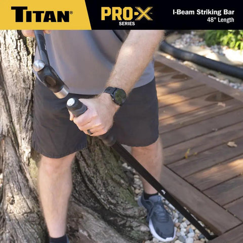 Person using Heavy Duty 48 Inch I Beam Striking Bar With Angled Chisel End And Reinforced Strike Cap outdoors against tree.