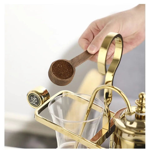 Top Shelf Siphon Coffee Maker serving up smooth brews with a hand pouring ground coffee into the glass chamber.