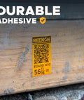 Close-up of durable adhesive label on wood marked with QR code, showcasing P1L Portable Bluetooth Thermal Construction Label Printer For Jobsites With QR Codes And One Click Labels Battery Powered Quick Templates Rugged Mobile Label Maker For Materials And Locations use.