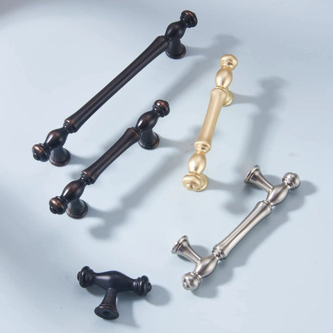 Various kitchen cabinet handles in brushed finishes, including brass, black, and chrome, displayed on a light surface.