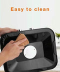 User cleaning the black interior of the Hassle Free Countertop Electric Food Dehydrator With Five Generous Removable Trays.