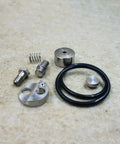 Waterjet check valve repair kit components, top-down view; metal fittings, spring, O-ring, and caps.