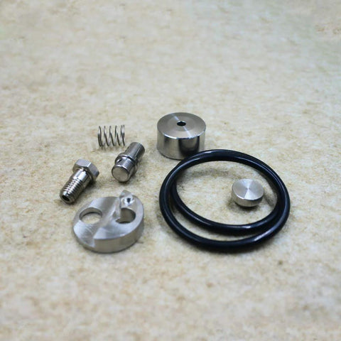 Waterjet check valve repair kit components, top-down view; metal fittings, spring, O-ring, and caps.