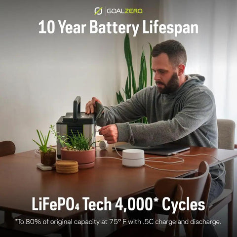 Yeti Portable Power Station 499 Watt Hour LiFePO4 Battery Water Resistant And Dustproof on table with man plugging in device