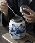 Hands opening Classic Blue And White Ceramic Tea Jar Big Boy Airtight Loose Tea Storage Caddy For Kitchen Pantry Organization.