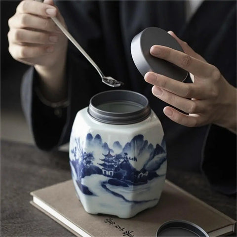 Hands opening Classic Blue And White Ceramic Tea Jar Big Boy Airtight Loose Tea Storage Caddy For Kitchen Pantry Organization.