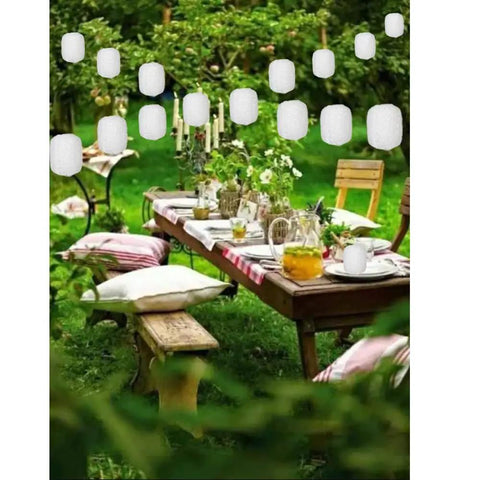 Outdoor garden with Ten Pack White Paper Lanterns 6.3 Inch Oval Hollow Hanging Lanterns for festive decor over a wooden table