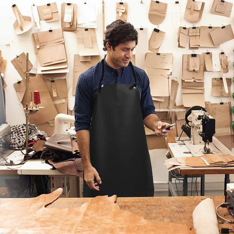Man wearing Heavy Duty PU Apron And Latex Gloves Set For Kitchen And Lab Use, standing in a workshop with leather tools.
