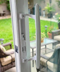 Super Slick White Diecast Sliding Patio Door Handle Set on glass door, designed for 1 to 1 1/8 inch thick panels, featuring smooth glide.