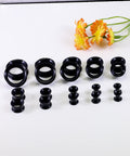Ultra Thin Silicone Ear Gauge Stretching Kit 4mm to 20mm Black Soft Flexible Tunnels Plugs displayed with orange flowers