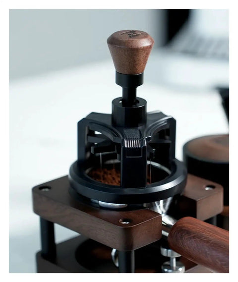 Heavy Duty 58 Millimeter Espresso Portafilter Needle Distributor With Built In Magnet resting on wood base with brown handle.