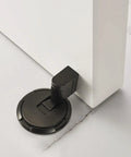 Kickass Magnetic Door Stopper Windproof Floor Hold Open Latch With Strong Adhesive Or Screw Mount For Easy No Sweat Install And Premium Heavy Duty Door Protection on a white door.