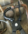 Amazon exhaust hanger removal pliers; black metal tool gripping a rubber exhaust hanger around a rusted exhaust pipe