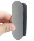 2 Pack Self Adhesive Pull Handles Gray For Cabinets Drawers And Doors Tool Free Installation No Drill Required Easy Sticky Mount Durable Grab Handles For Quick Access And Easy Pull In Any Room. Gray self-adhesive pull handle shown in hand, vertical view for cabinet or drawer use.