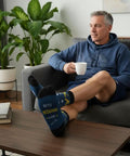 Man relaxing on sofa wearing Mechanic Socks Gift Set For Men And Women, Best Car Auto Repair Mechanic Appreciation Gift socks.