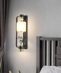 Slick Contemporary Wall Sconce With A Heavy Duty Black Iron Bracket And Clear Glass Shade For Pure Indoor Outdoor Vibes mounted beside bed.