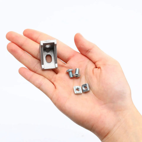 Hand holding parts from 50 Piece Aluminum Profile Connector Kit For 6mm Slot Extrusions White Corner Brackets With 100 M5 T Nuts And 100 M5 X 8mm Hex Screws For DIY CNC Printer Frame And Robotics Build