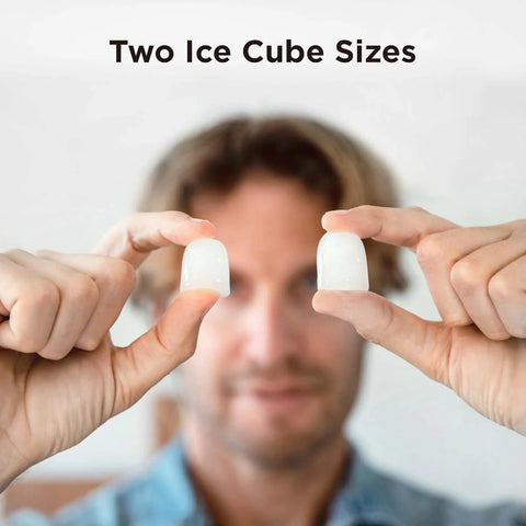 Two bullet ice cubes held between fingers in close-up, clear white ice.
