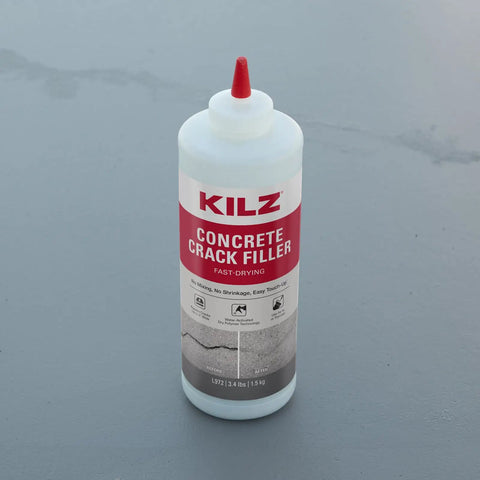 No Sweat Gray Concrete Crack Filler Dry Powder Blend Needs No Mixing Seals Cracks Up To Two Inches Wide in a bottle on a gray surface.