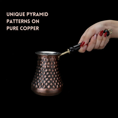 Hand holding Handmade Copper Turkish Cezve with pyramid pattern and antique finish, part of set for rich Turkish coffee brewing.